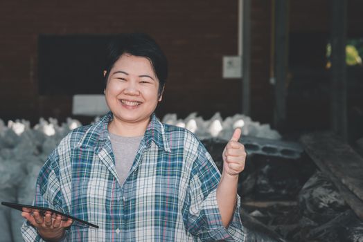 Asian woman smart farmer agriculturist happy at a Fertilizer composting plant with Organic Fertilizer, Compost (Aerobic Microorganisms) from animal waste for use in the organic agriculture industry