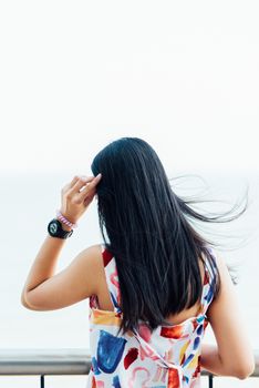 Asian pretty woman with hair blown relax at sea viewpoint with loneliness and lonely emotion in concept travel, vacation, leisure in life