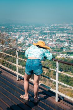 Asian pretty cute woman with hat relax and use smartphone at seaside city landscape viewpoint on mountain with happy and freedom emotion in concept travel, vacation, leisure in life