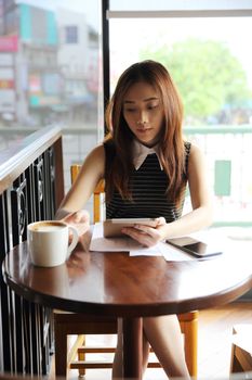 Asian woman drinking coffee with tablet