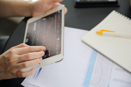 Woman hand Trading online on tablet with business paper and coffee