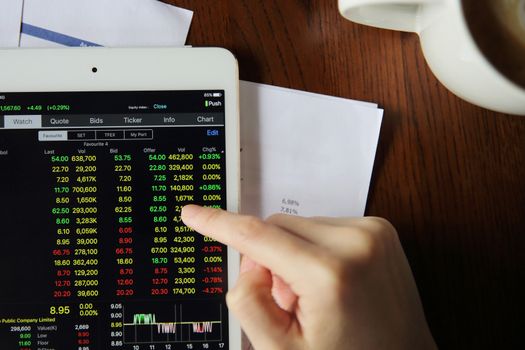 Woman hand Trading online on tablet with business paper and coffee