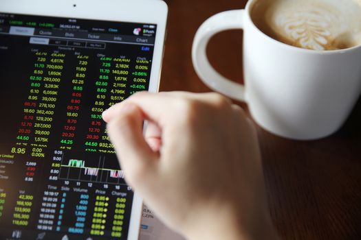 Woman hand Trading online on tablet with business paper and coffee