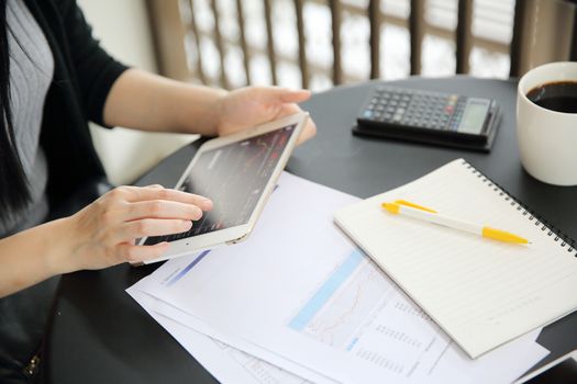 Woman hand Trading online on tablet with business paper and coffee