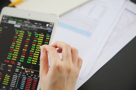 Woman hand Trading online on tablet with business paper and coffee