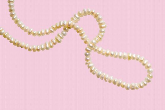 Natural pearls necklace on a pink stripped background