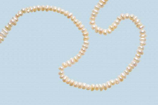 Natural pearls necklace on a sky blue stripped background