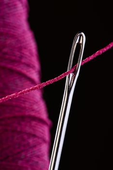 Macro of a needle and a purple roll of elastic thread