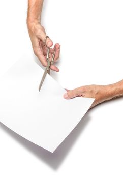 A man is cutting a sheet of white paper using  metallic scissors, on white background