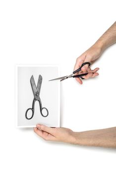 A woman is cutting a black and white photo using  metallic scissors, isolated on white background