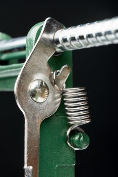 Macro detail of a metallic spring on a cutting machine, on black background