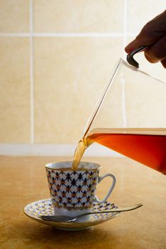 Pouring hot coffee in an elegant porcelain cup, in the kitchen