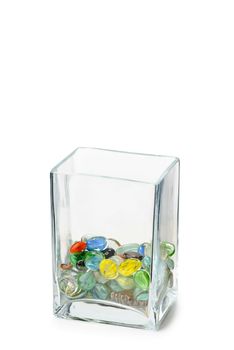 A Parallelepipedic transparent crystal vase isolated on white background, half full of colored glass beads