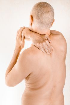 Man massaging his top back, the trapezius muscle, because of a thoracic vertebrae pain due to a displacement of a dorsal vertebra rubbing on a nerve