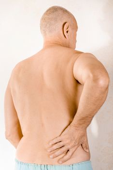 Man massaging the low back because of a painful lumbago due to a displacement of the lumbar vertebrae