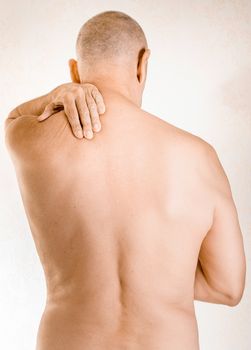 Man massaging his top back, the trapezius muscle, because of a thoracic vertebrae pain due to a displacement of a dorsal vertebra rubbing on a nerve