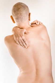 Man massaging his top back, the trapezius muscle, because of a thoracic vertebrae pain due to a displacement of a dorsal vertebra rubbing on a nerve