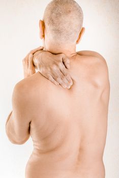 Man massaging his top back, the trapezius muscle, because of a thoracic vertebrae pain due to a displacement of a dorsal vertebra rubbing on a nerve