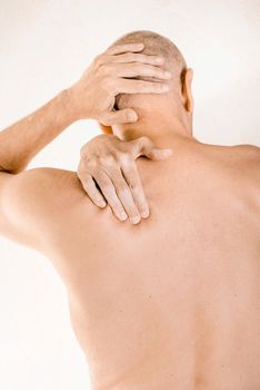 Man massaging his top back, the trapezius muscle, because of a thoracic vertebrae pain due to a displacement of a dorsal vertebra rubbing on a nerve