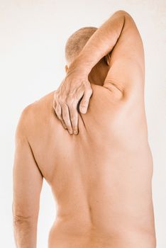 Man massaging his top back, between the shoulders, because of a thoracic vertebrae pain due to a displacement of a dorsal vertebra rubbing on a nerve