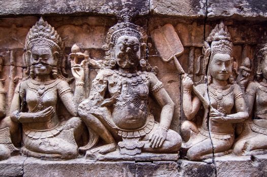 Bas relief carving of an Asura deity being fanned cool by beautiful women on a wall of the ancient Khymer temple of Banteay Strei in the city of Angkor in Cambodia.  