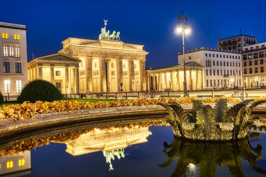 The famous Brandenburger Tor in Berlin at night, reflected in a fountain