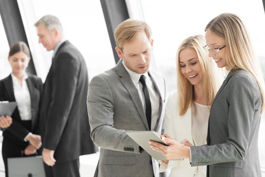 Three smart employees discussing documents using tablet pc at meeting