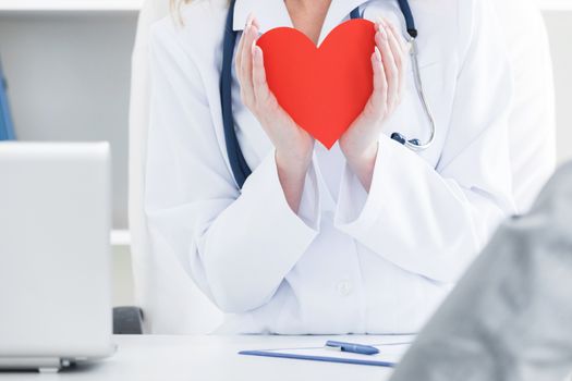 Doctor holding a red heart at hospital office, medical health care and doctor staff service concept
