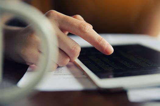 Woman hand Trading online on tablet with business paper and coffee