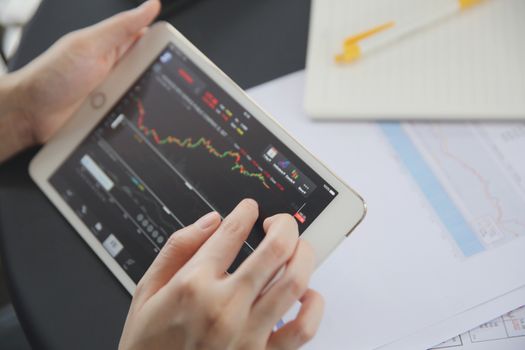 Woman hand Trading online on tablet with business paper and coffee