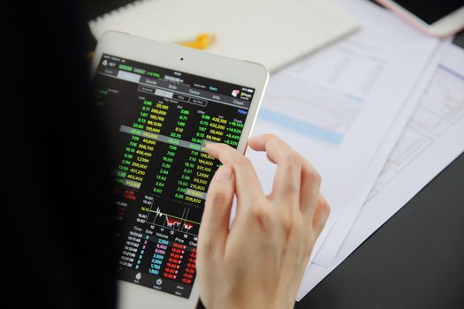 Woman hand Trading online on tablet with business paper and coffee