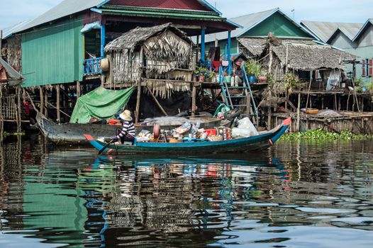 Kampong Phluk, Cambodia - December 4, 2011:  A woman paddling a heavily laden wooden boat through the floating village of Kampong Phluk on the Tonlie Sap lake near Siem Reap, Cambodia.