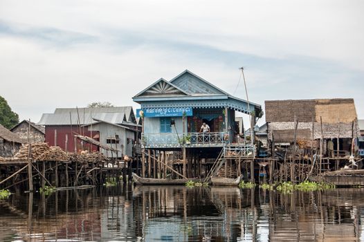 Kampong Phluk, Cambodia - December 4, 2011:  A man relaxing on the terrace of the Cambodian People's Party offices built on stilts in the floating village of Kampong Phluk on the Tonle Sap lake in the Siem Reap district of the country.  