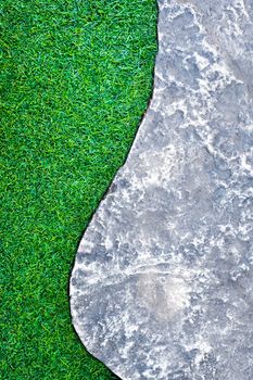 Rough surface texture of gray color concrete pathway brick and green color of plastic artificial grass