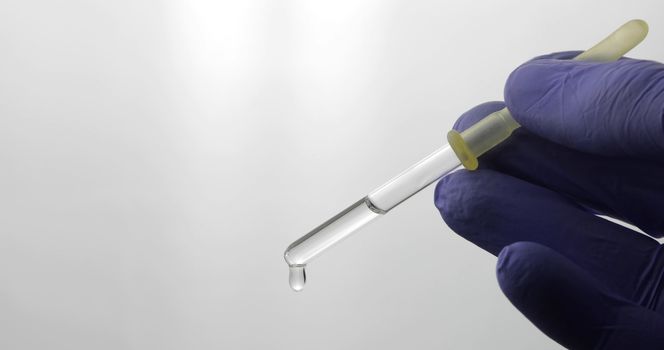 Hand in medical glove drip drop from pipette. Close-up video. Liquid drop over white background. Medical and chemistry laboratory research