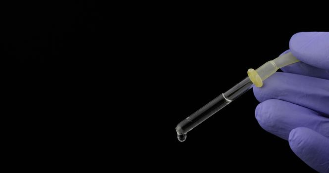 Hand in medical glove drip drop from pipette. Close-up video. Liquid drop over black background. Medical and chemistry laboratory research