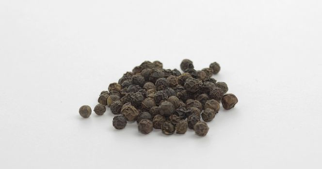 Black pepper. Peas with spices. Herbal spice, aromatic seasoning for food preparation and cooking, macro shot against a white background