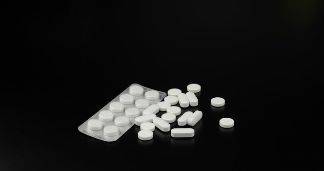 Medical round and oval pills on black background.