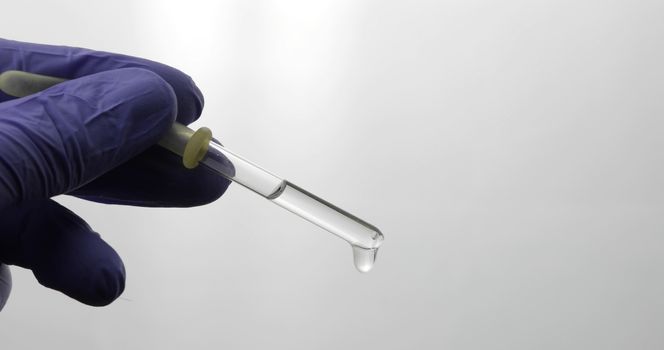 Hand in medical glove drip drop from pipette. Close-up video. Liquid drop over white background. Medical and chemistry laboratory research