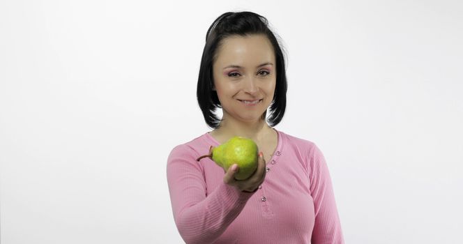 Young beautiful woman with big, fresh, juicy, green pear. Offer bite to viewer. Healthy nutrition