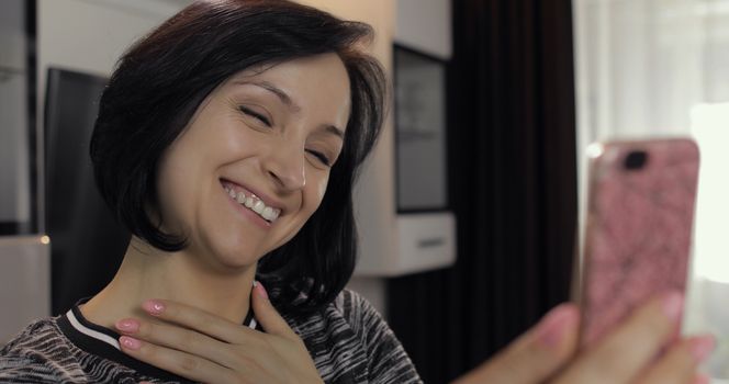 Portrait of pretty caucasian young brunette woman having video chat using smartphone enjoying chatting to friend