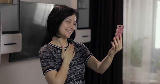 Portrait of pretty caucasian young brunette woman having video chat using smartphone enjoying chatting to friend