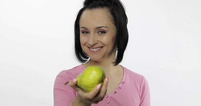 Young beautiful woman with big, fresh, juicy, green pear. Offer bite to viewer. Healthy nutrition