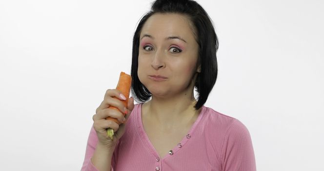 Young beautiful woman eating big carrot. Healthy nutrition. Model eating vegetables