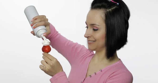 Young beautiful woman with fresh and juicy strawberry with whipped cream.