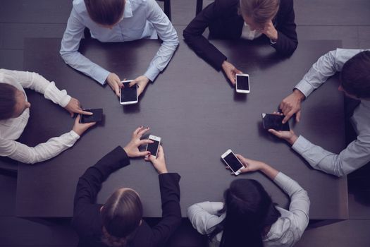Business people with blank phones sitting around the table using app, top view