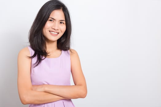 Portrait Asian beautiful young woman standing smile seeing white teeth, She crossed her arms and looking at camera, shoot photo in studio on white background. copy space to put text