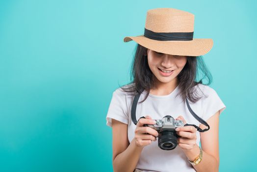 Traveler tourist happy Asian beautiful young woman smile in summer hat standing with mirrorless photo camera, shoot photo in studio on blue background with copy space for text