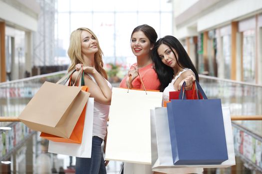 Young beautiful happy girls showing shopping purchase bags in mall