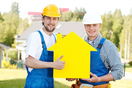 Workers with yellow house model building construction concept